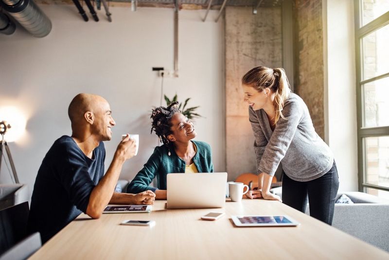 Business colleagues with coffee and laptop at meeting table